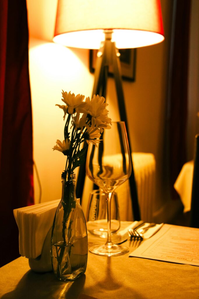 Warm and intimate table setup with flowers, wine glass, and soft lighting, perfect for a romantic dinner.